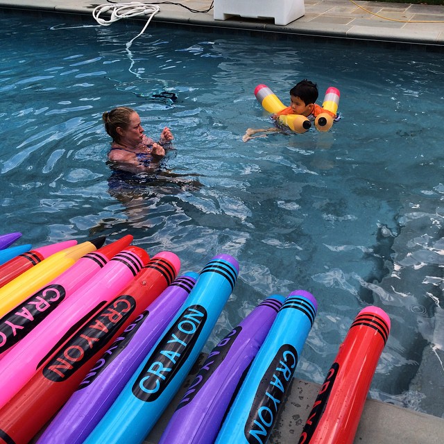 a group of people swimming in a large pool filled with swimming floats