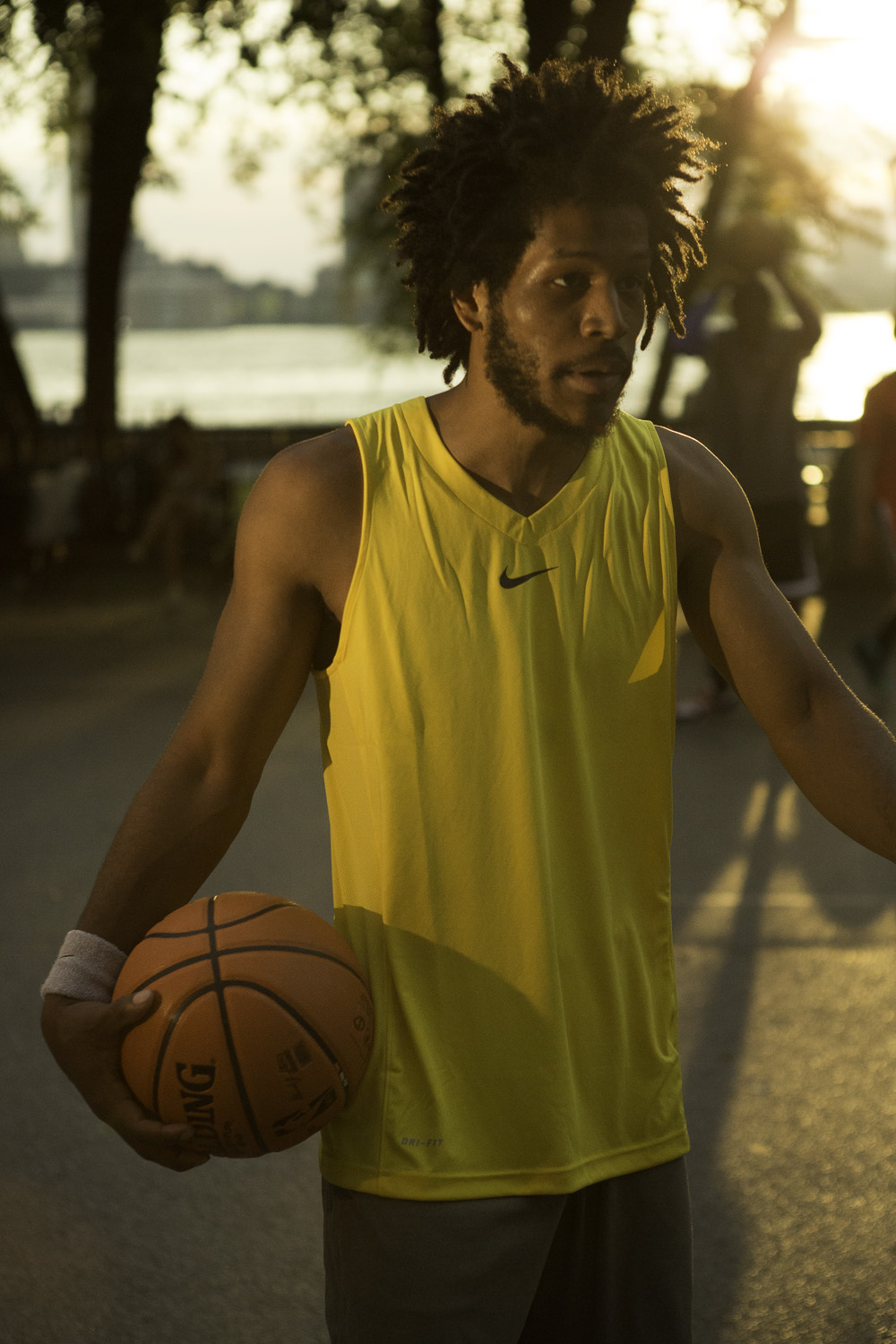 a basketball player wearing a yellow shirt is holding a ball in his right hand