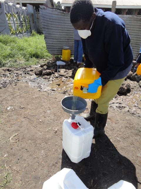 man in black jacket and mask collecting water from a yellow container