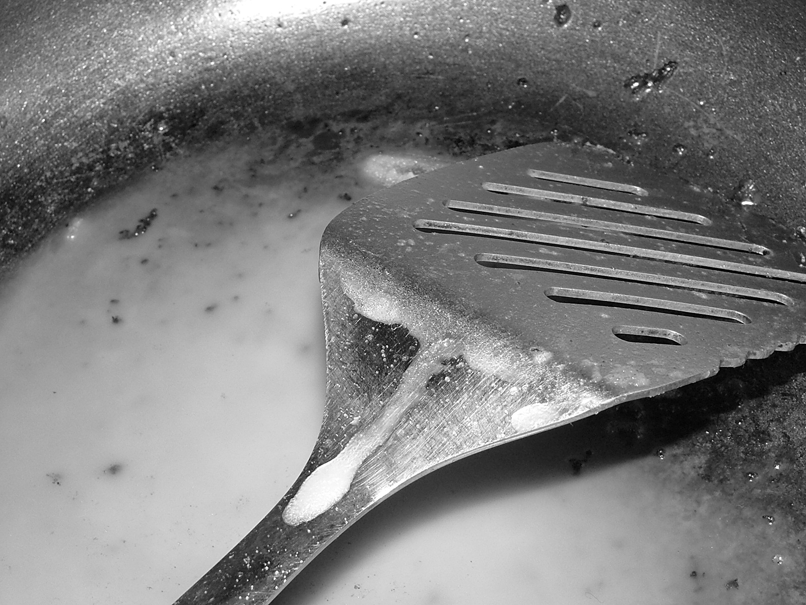 a frying pan filled with liquid and a cooking utensil