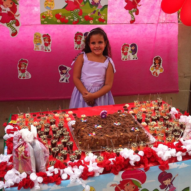 the little girl is standing in front of a very pretty cake