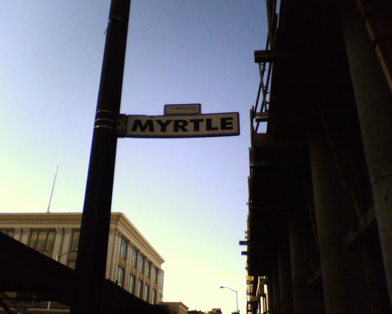 a close up of street sign with buildings in the background