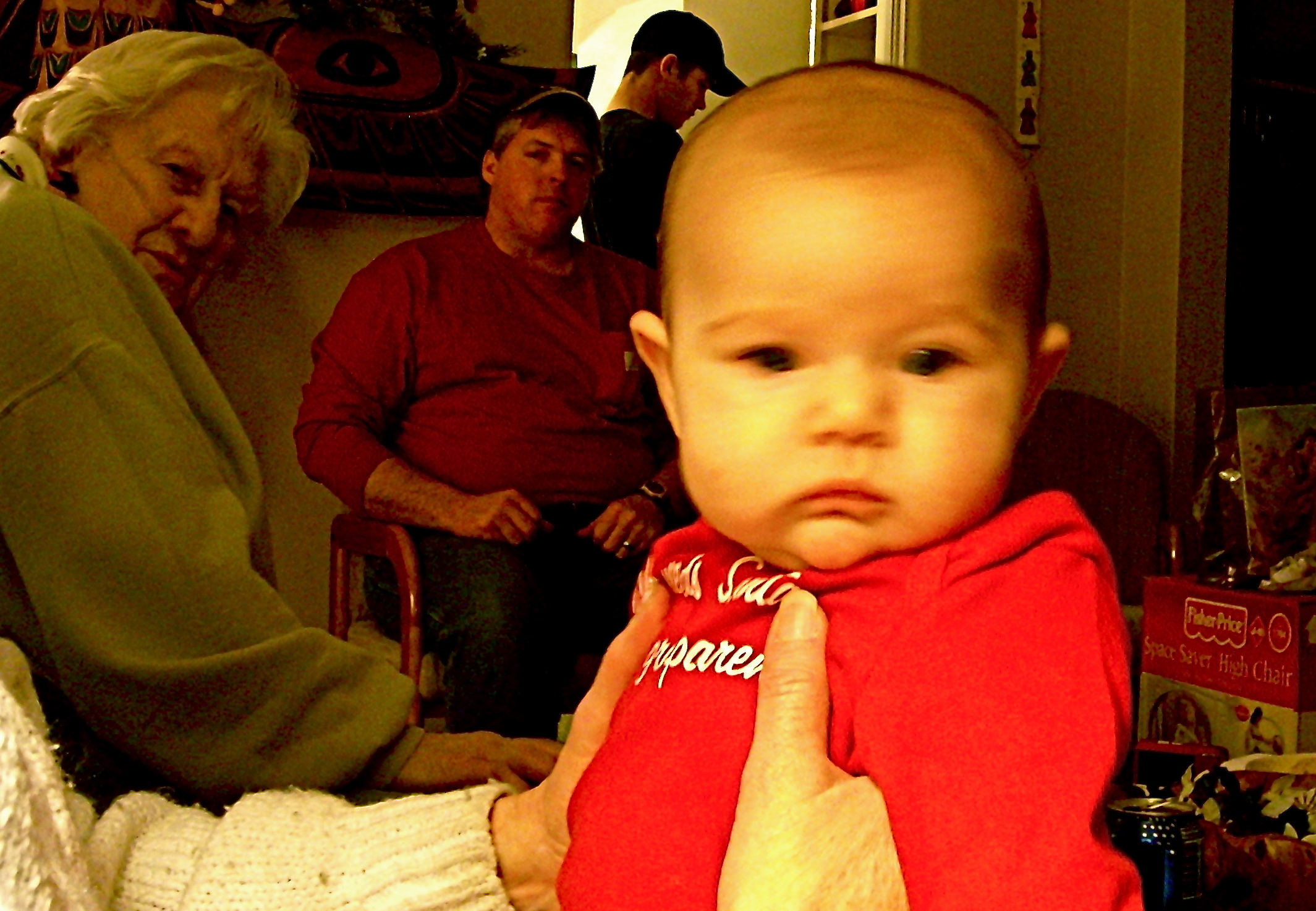 a baby in a red shirt sitting with others