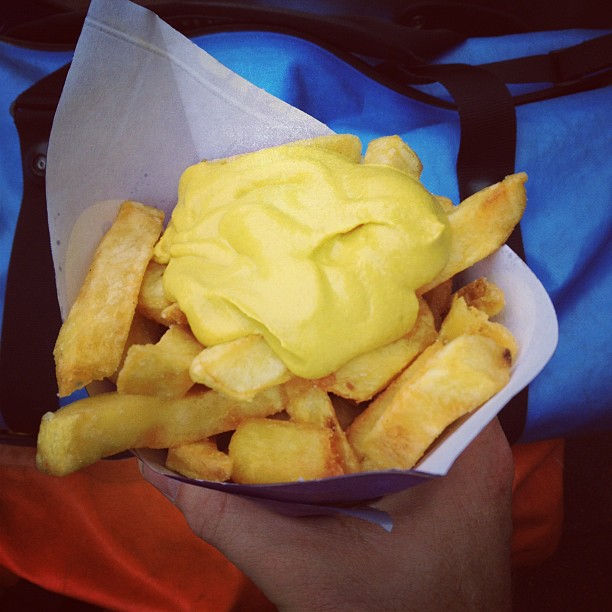 there is a bowl of fries that have yellow sauce on it