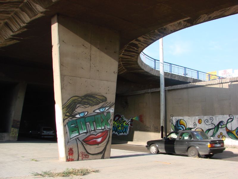 a car is parked under an overpass with graffiti on the walls