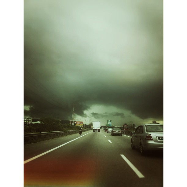 a storm rolling in behind a van on the highway