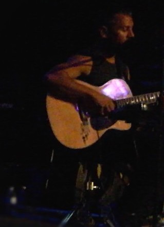 a man playing the guitar on stage at a concert