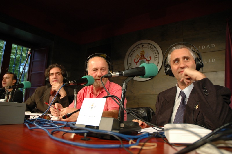 three men sitting at a desk with headphones on