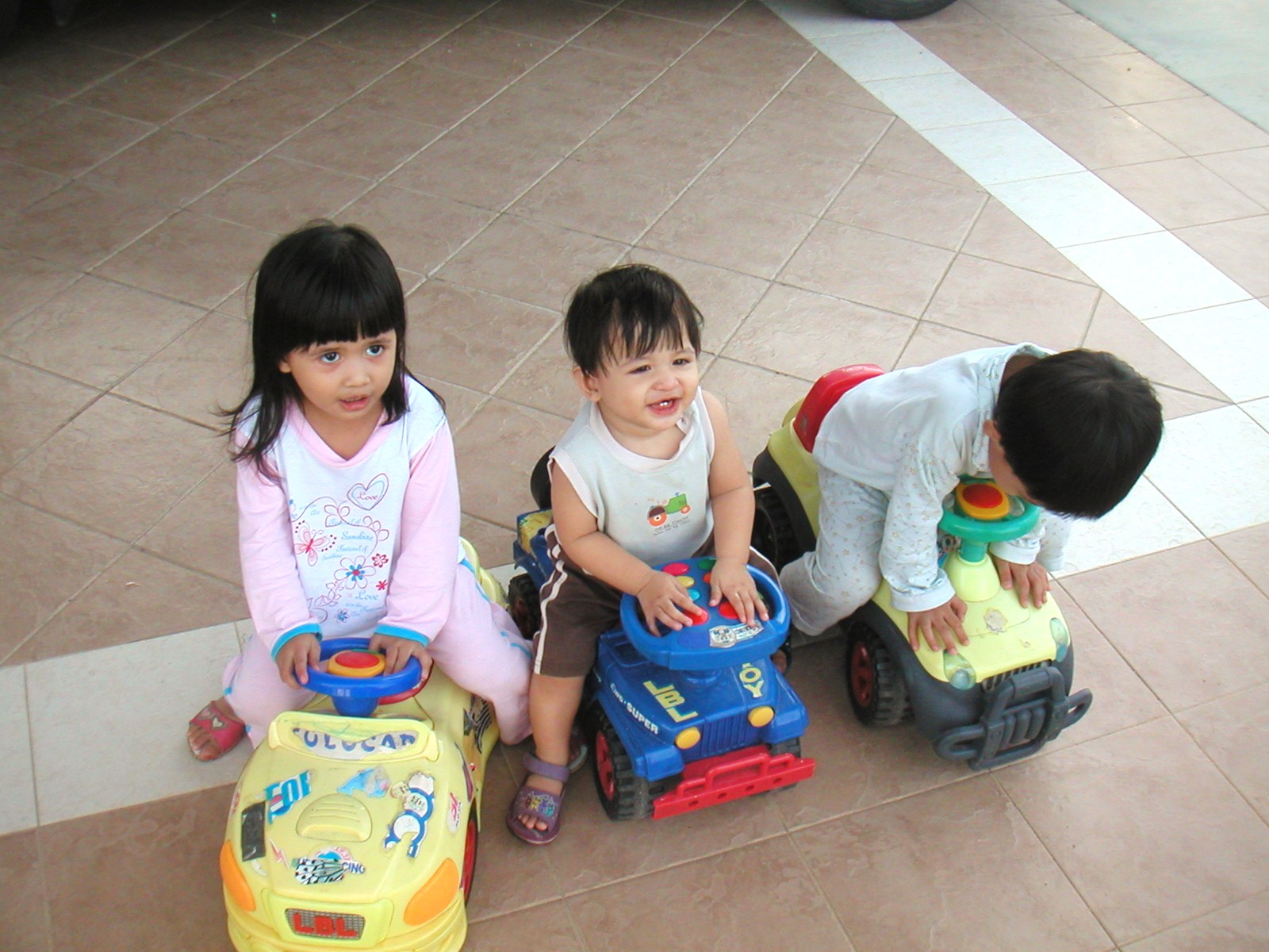 three children are sitting on little toys