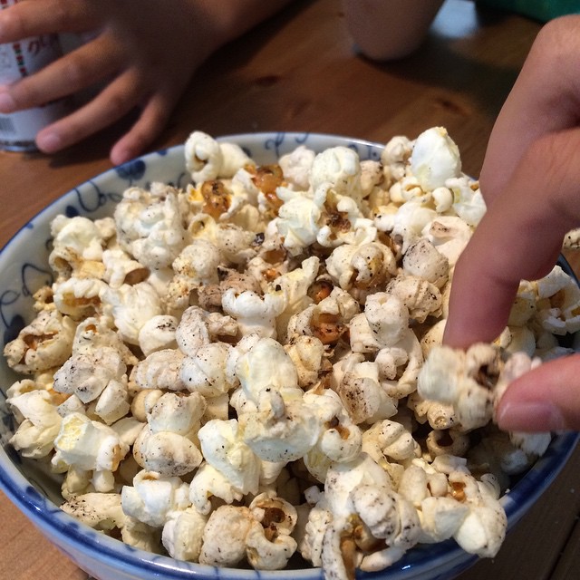 a hand is touching a popcorn bowl