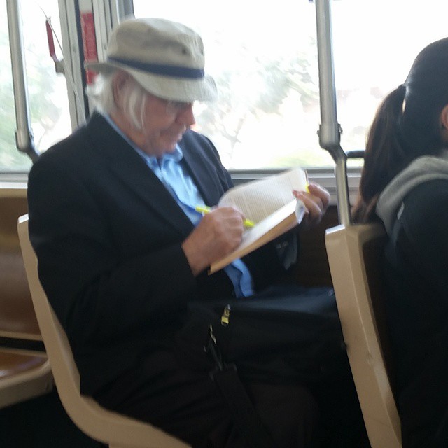 an older person in hat and glasses sitting in a seat on a bus