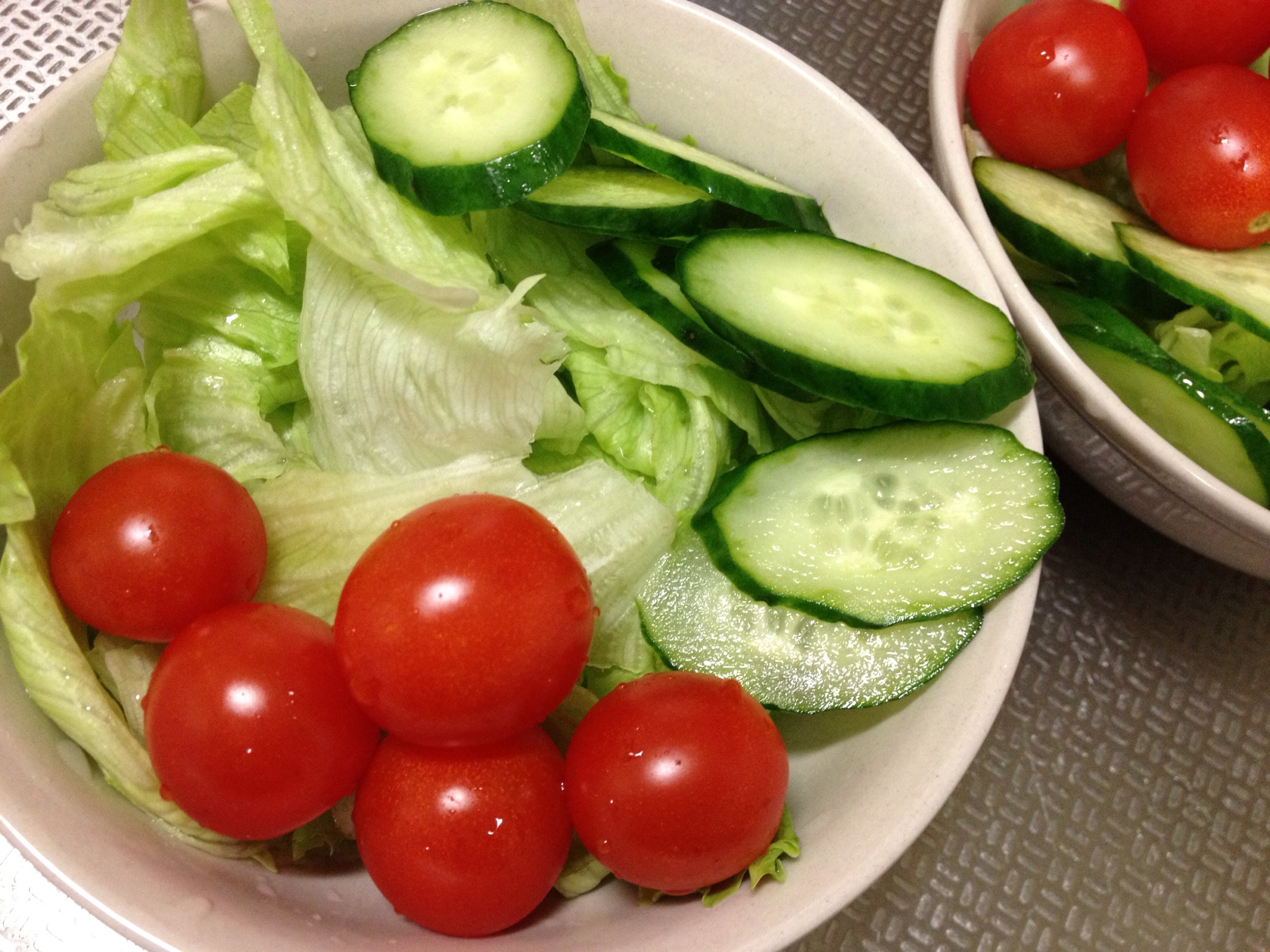 a salad consisting of lettuce, cucumbers and tomatoes in bowls