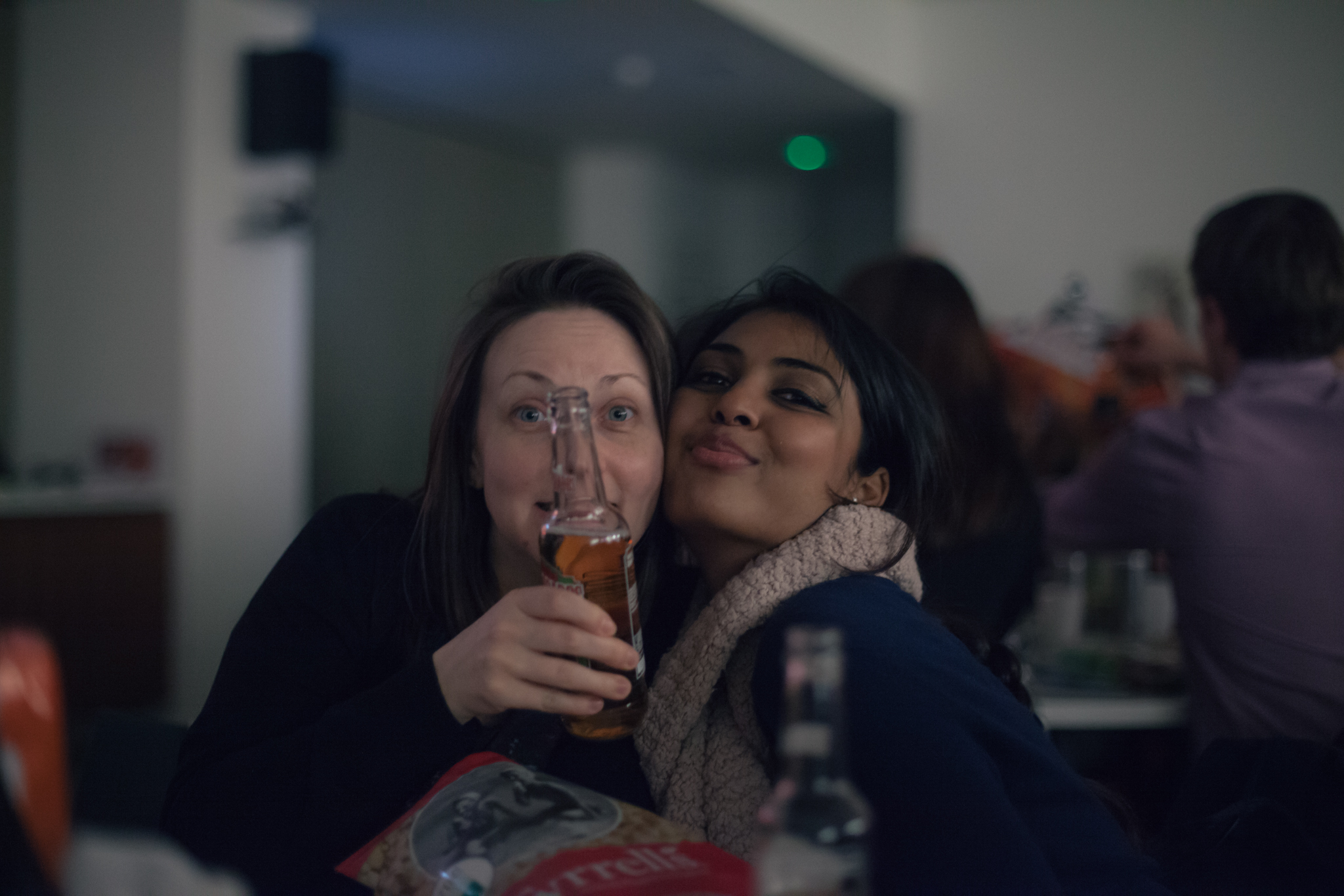 two woman smile while holding a beer