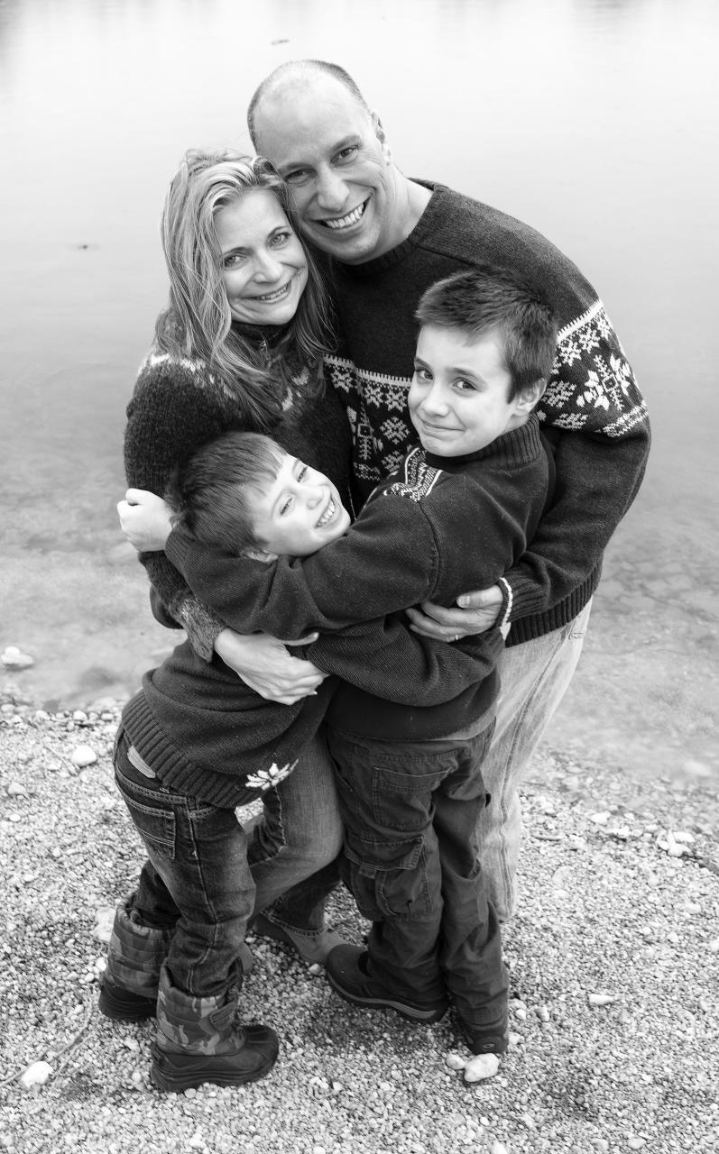 a family is hugging while standing near the water