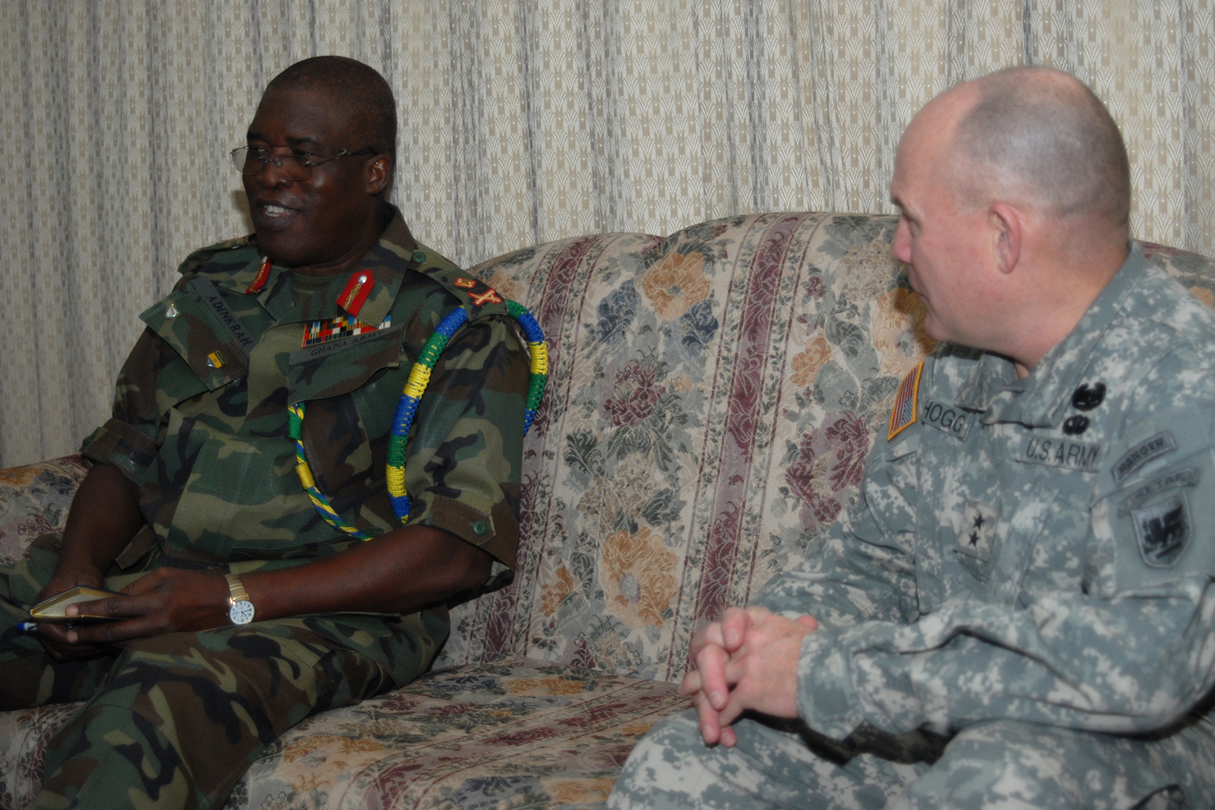 man in uniform sitting on a couch talking with another man