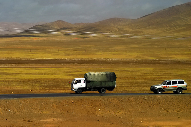 two white trucks driving next to each other on a road