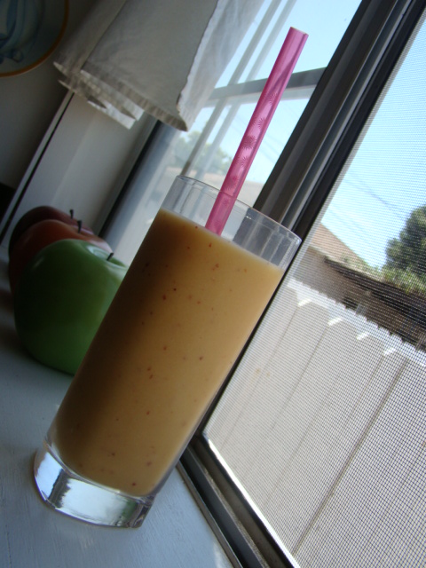 glass of orange juice next to fruit outside the window