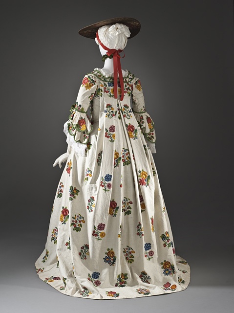 an antique dress with flowers and bonnet on display