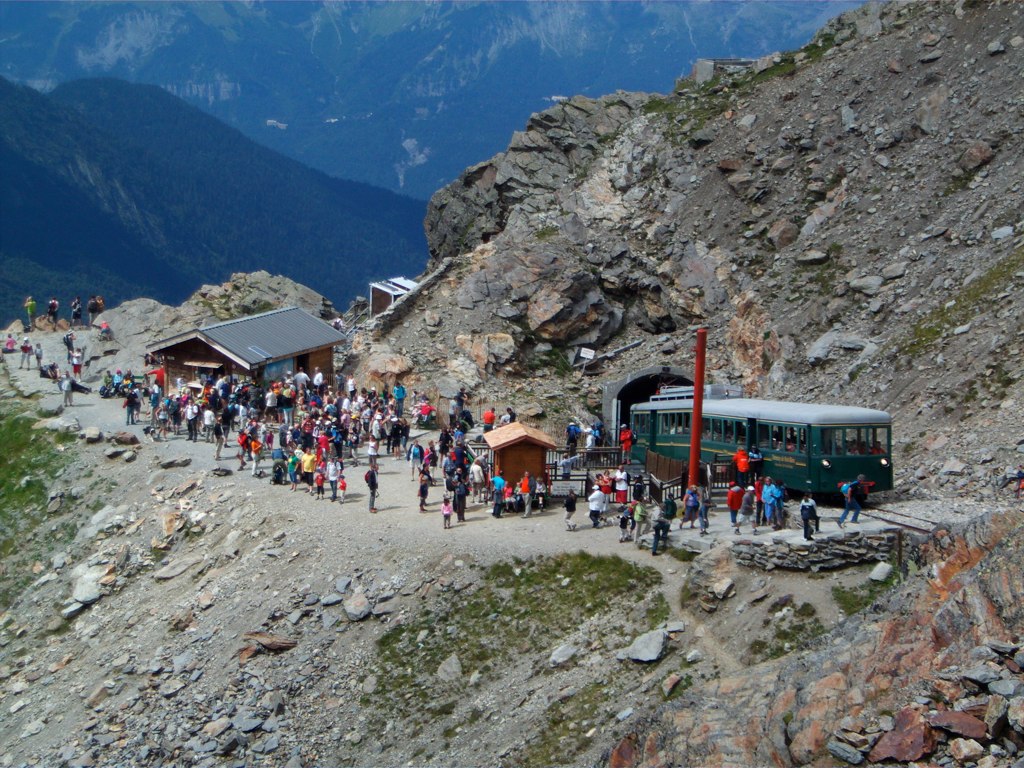 a crowd of people walk on a rocky path in the mountains
