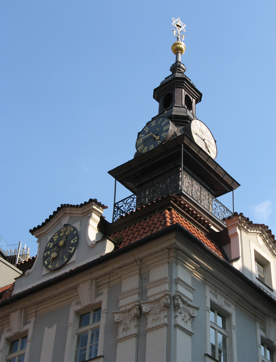 the clock tower atop a white building has gold and black designs