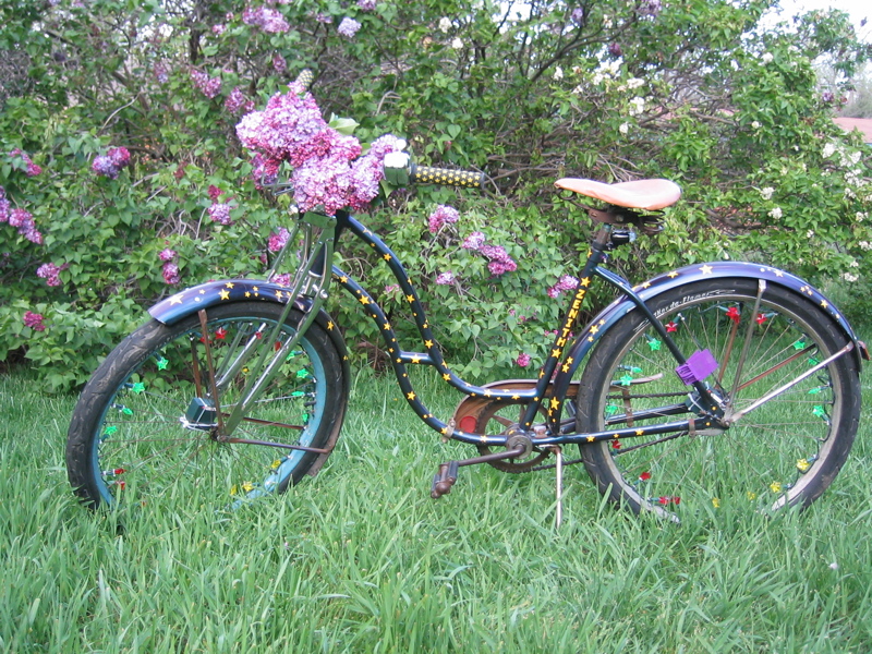 a decorated bicycle parked near a flower bush