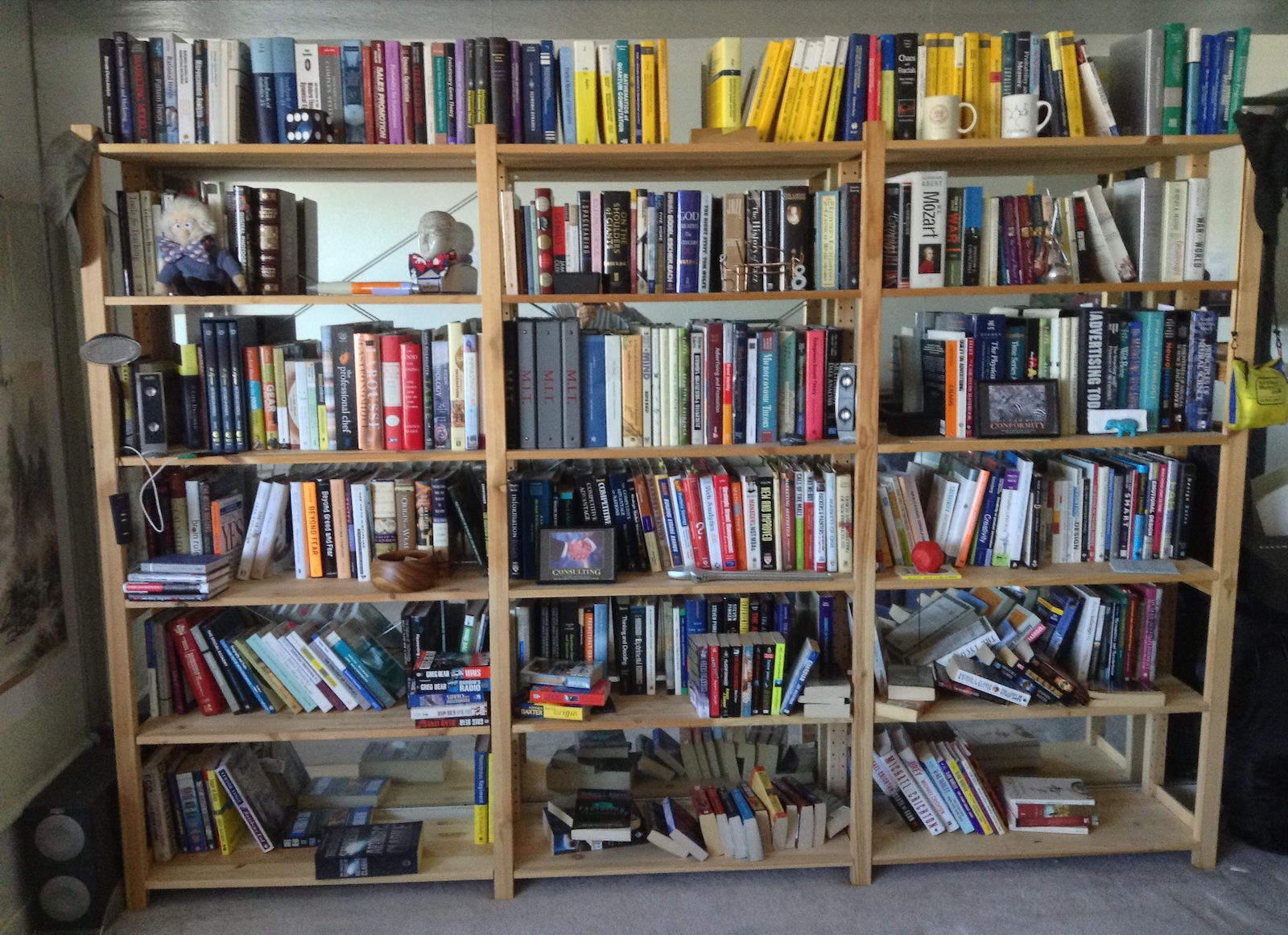 many books on a bookcase by some chairs