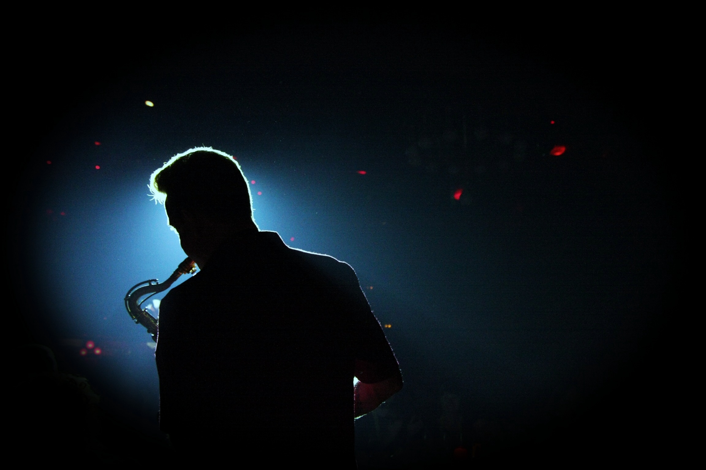 a man playing saxophone in the dark on stage