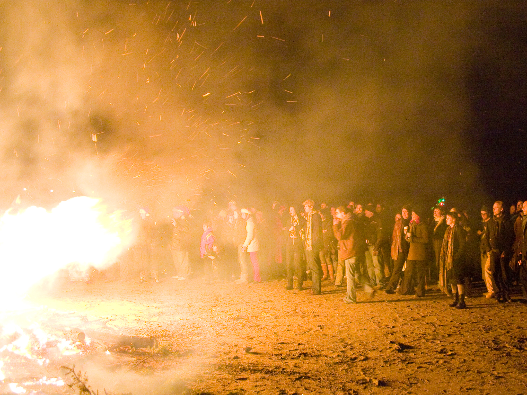 people are gathered around a bonfire in the dirt