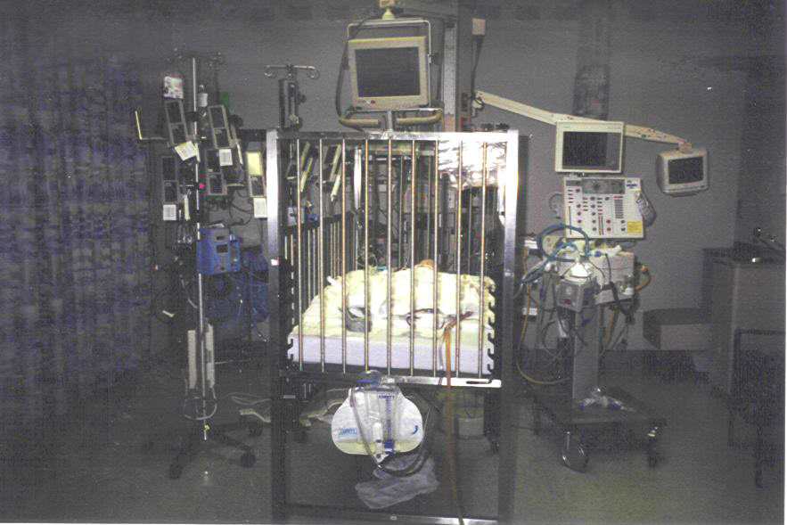 the baby is laying in a cage with many machines on it