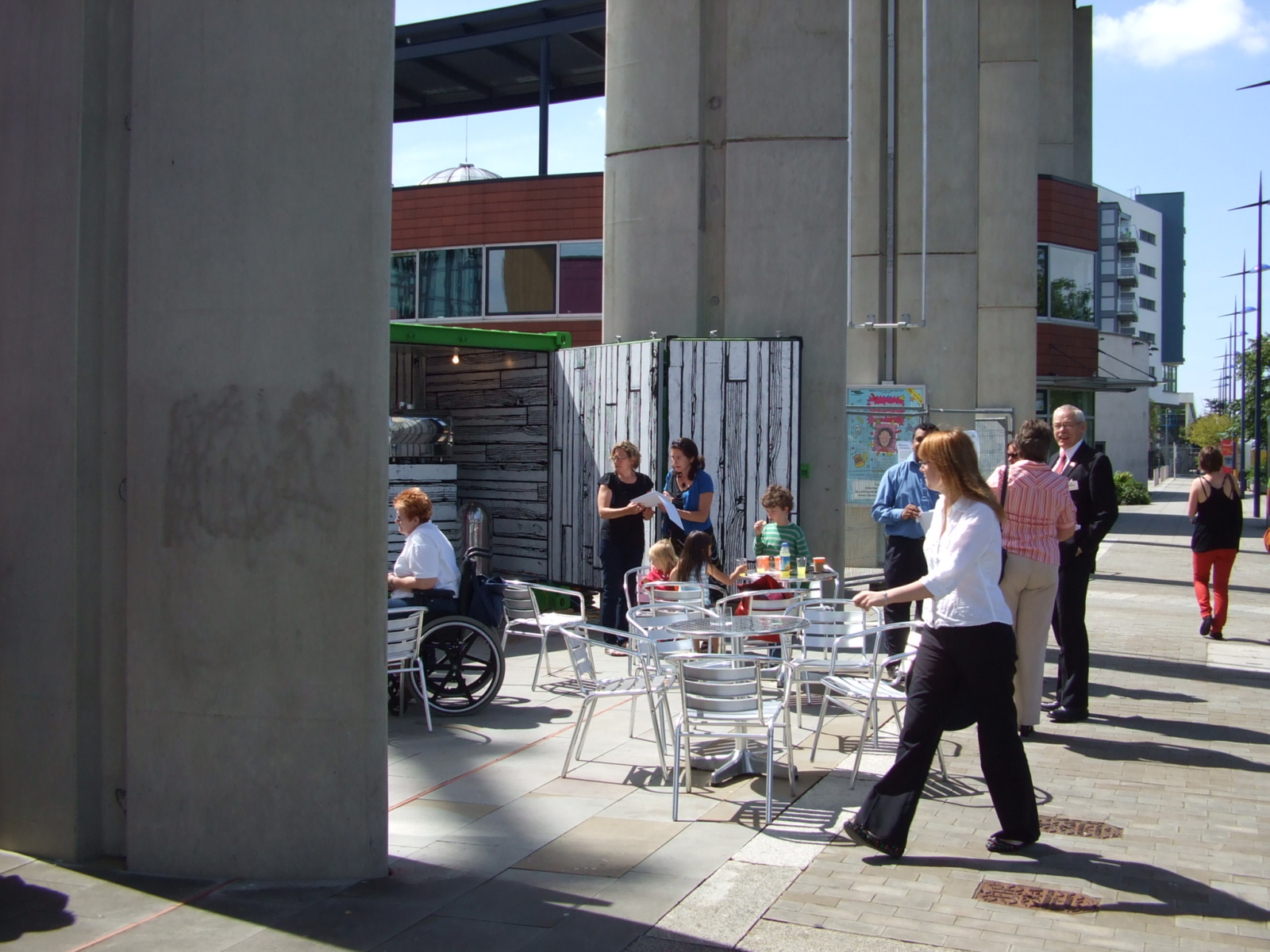 people walk down the sidewalk next to an outdoor dining area