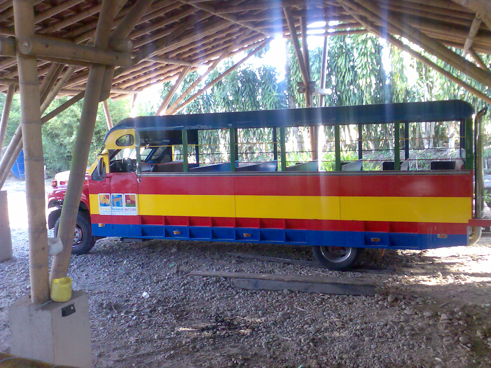 a red, yellow and blue bus is under a roof