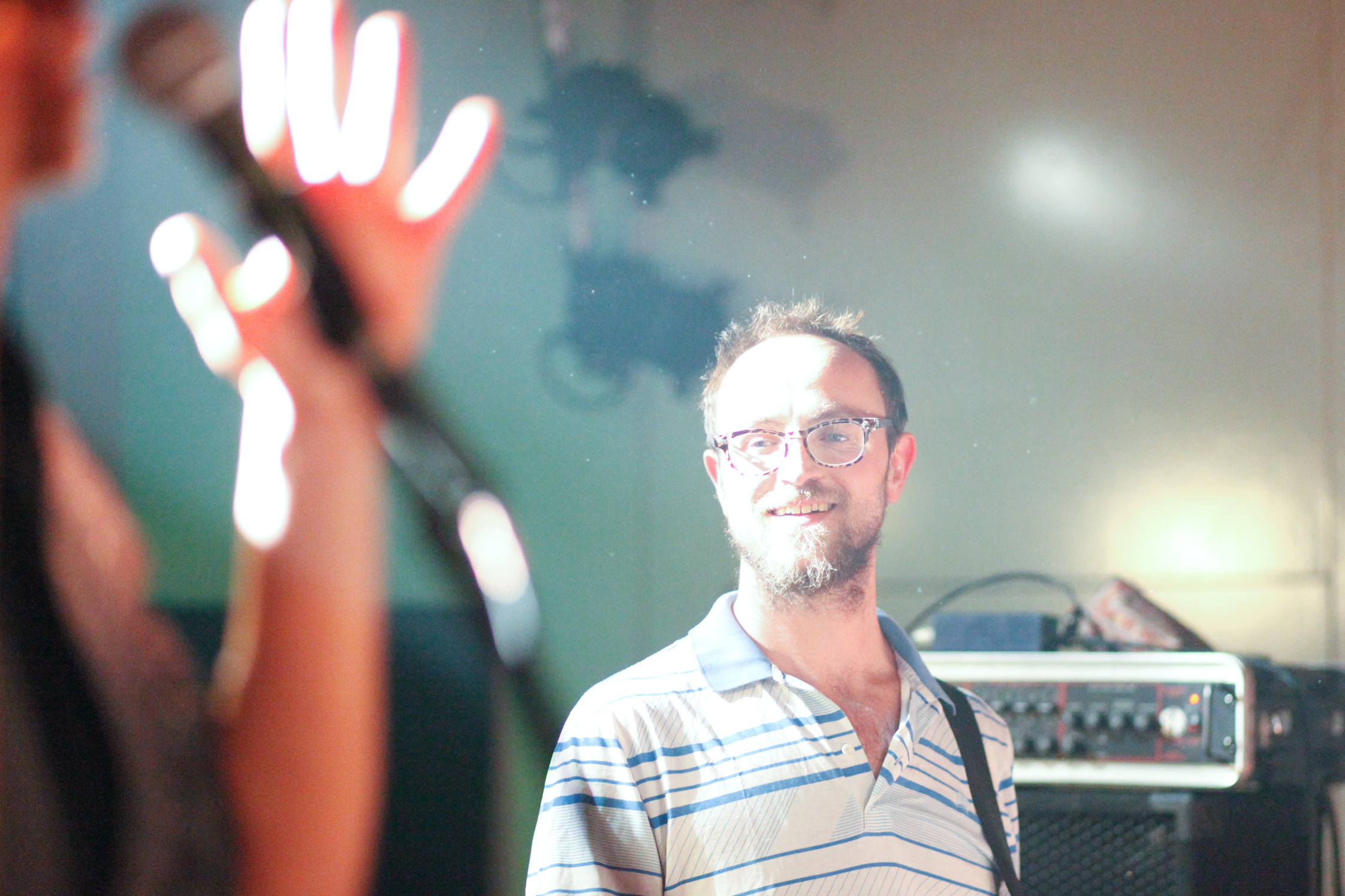 a man with glasses standing by a music mixer