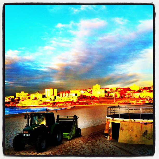 a tractor is on the beach and a sunset is in the background