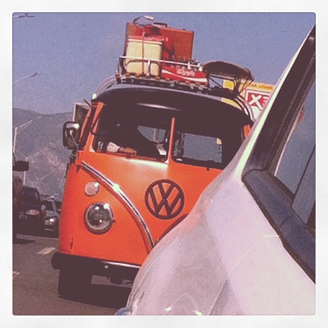 a vw van carrying luggage drives down the street