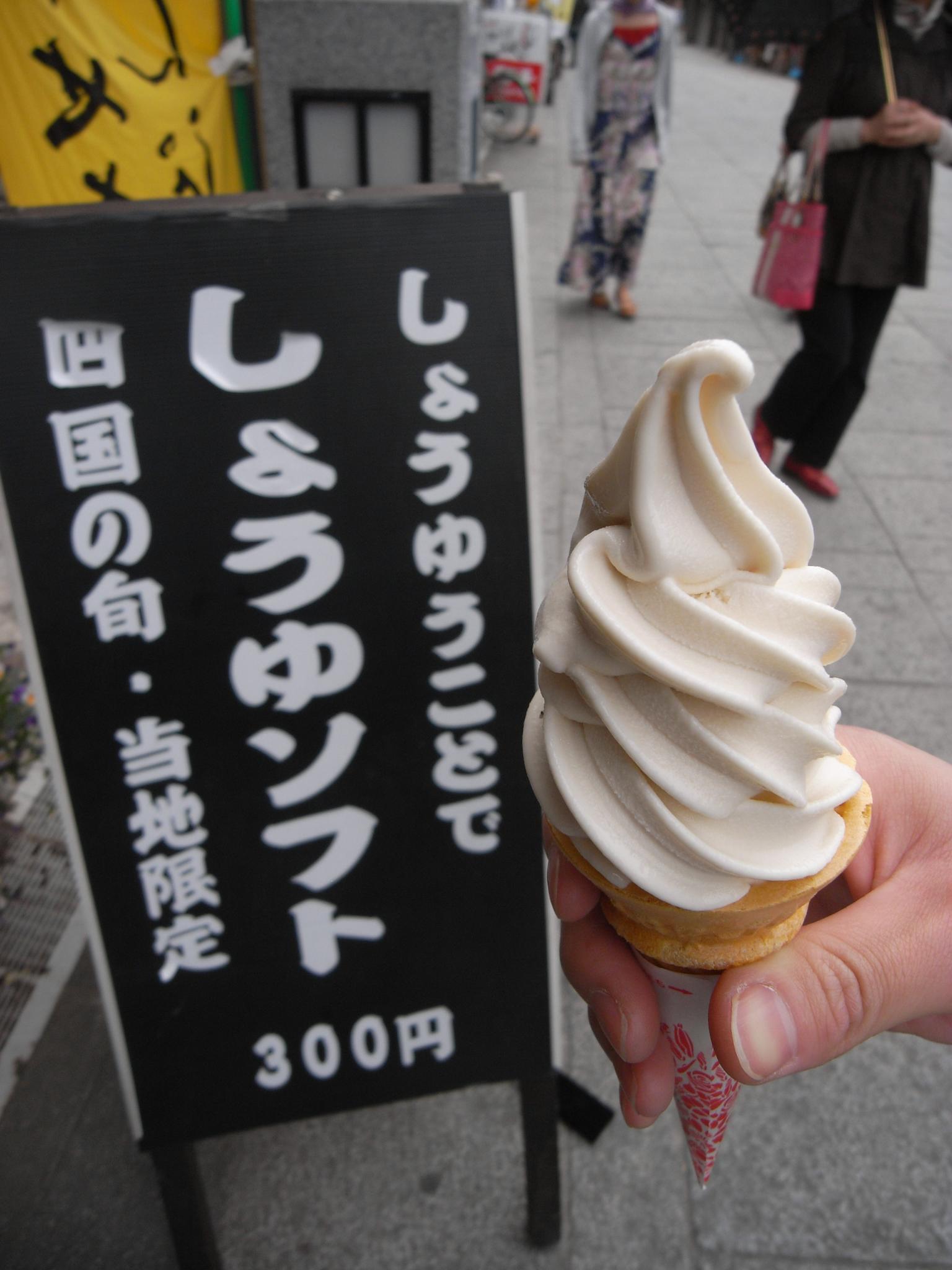 a person holding up a cupcake topped with white frosting