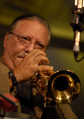 a man playing the trombone in front of some microphones
