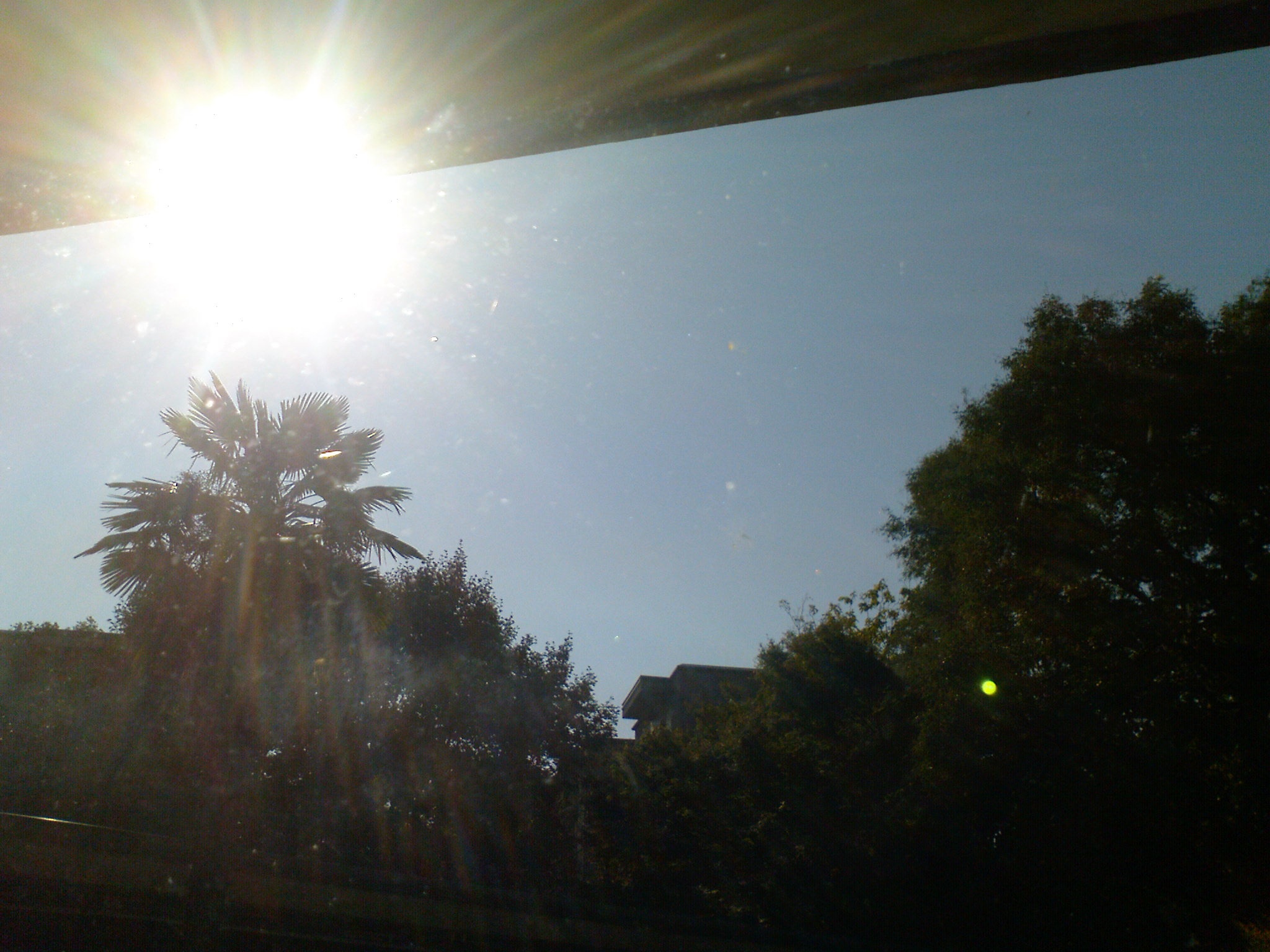 sunlight reflects off of the blue sky as seen from under an awning