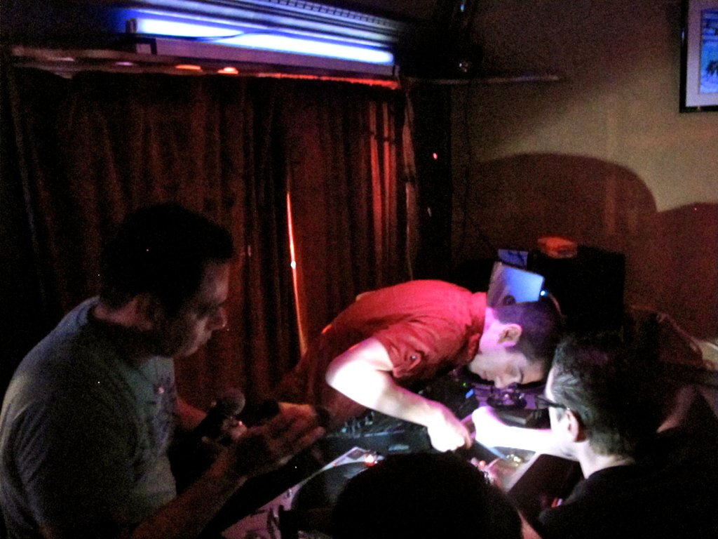 people standing around a dimly lit room playing with wii motes