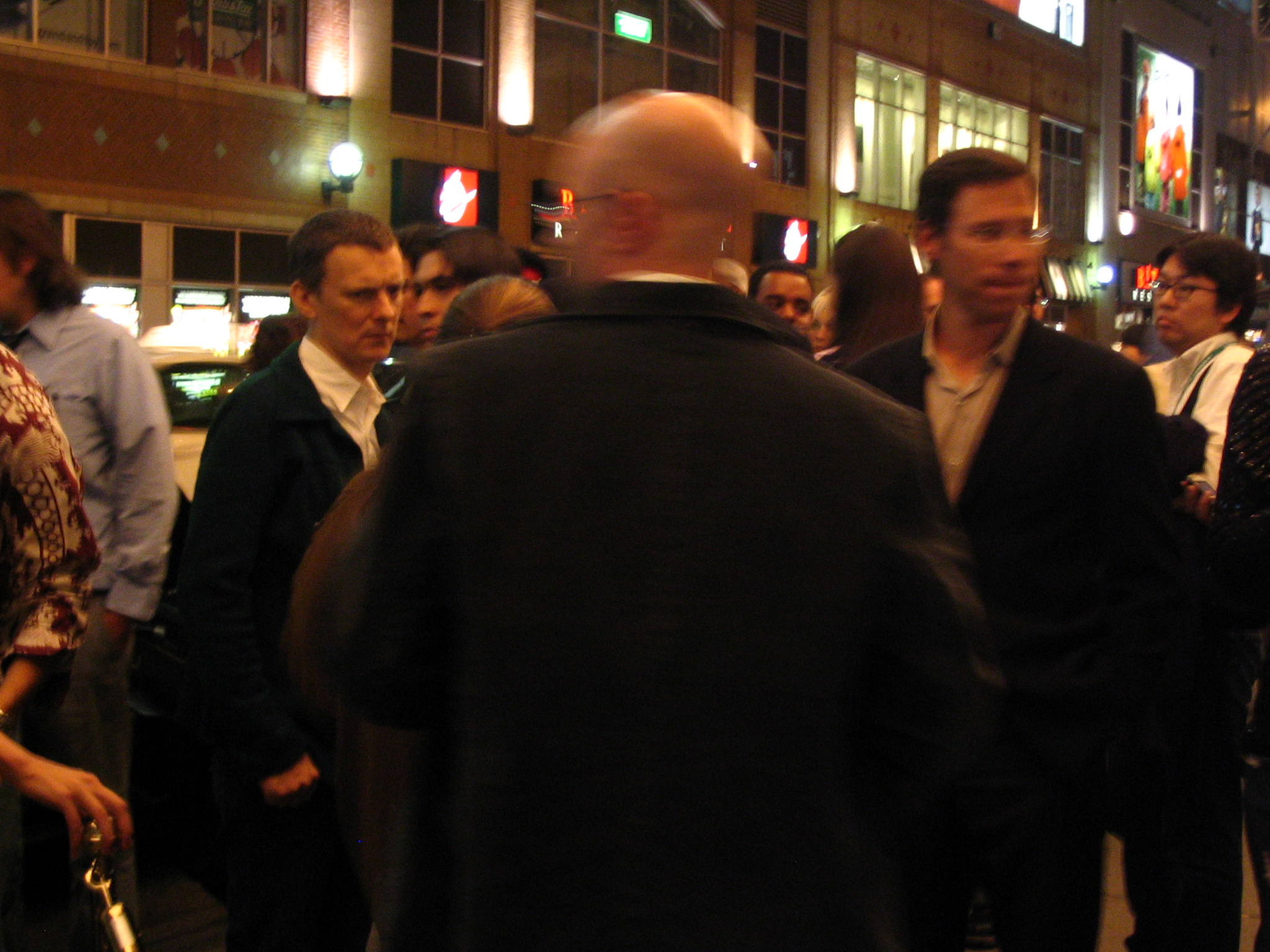 several people walking along the side of a busy street at night