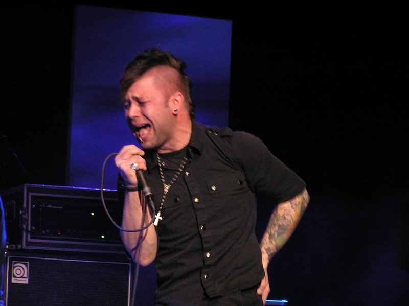 a man singing into a microphone with a band in the background