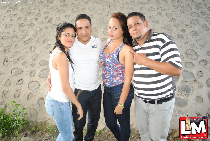 four people are posing together on a beach