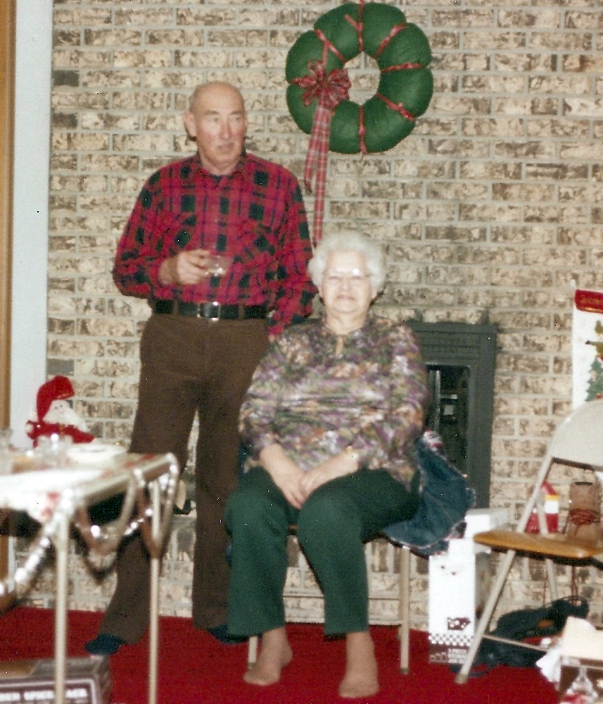 a man and woman stand in front of a fireplace decorated with christmas decorations