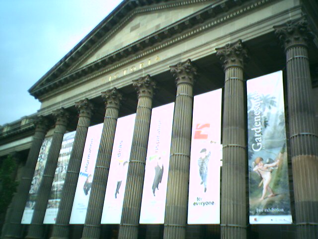 large building with columns, posters and a sky background