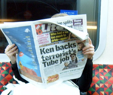 person with newspaper on their face sitting on a train seat
