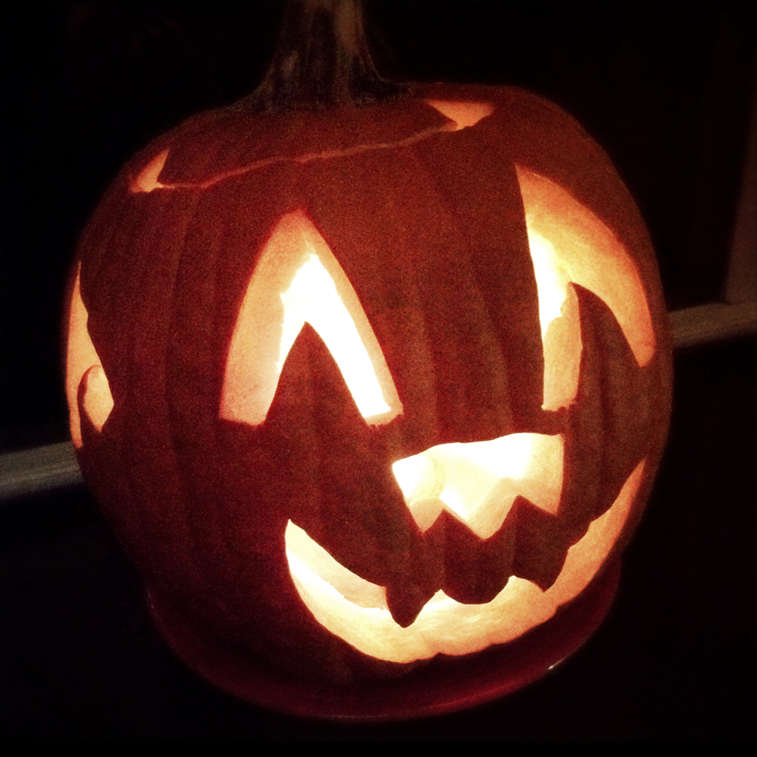 a carved pumpkin with glowing eyes in the dark
