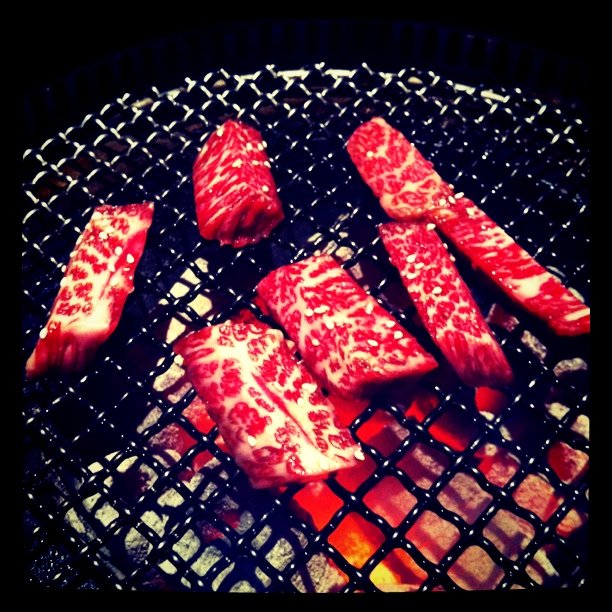 steaks being cooked on a grill and some red meat