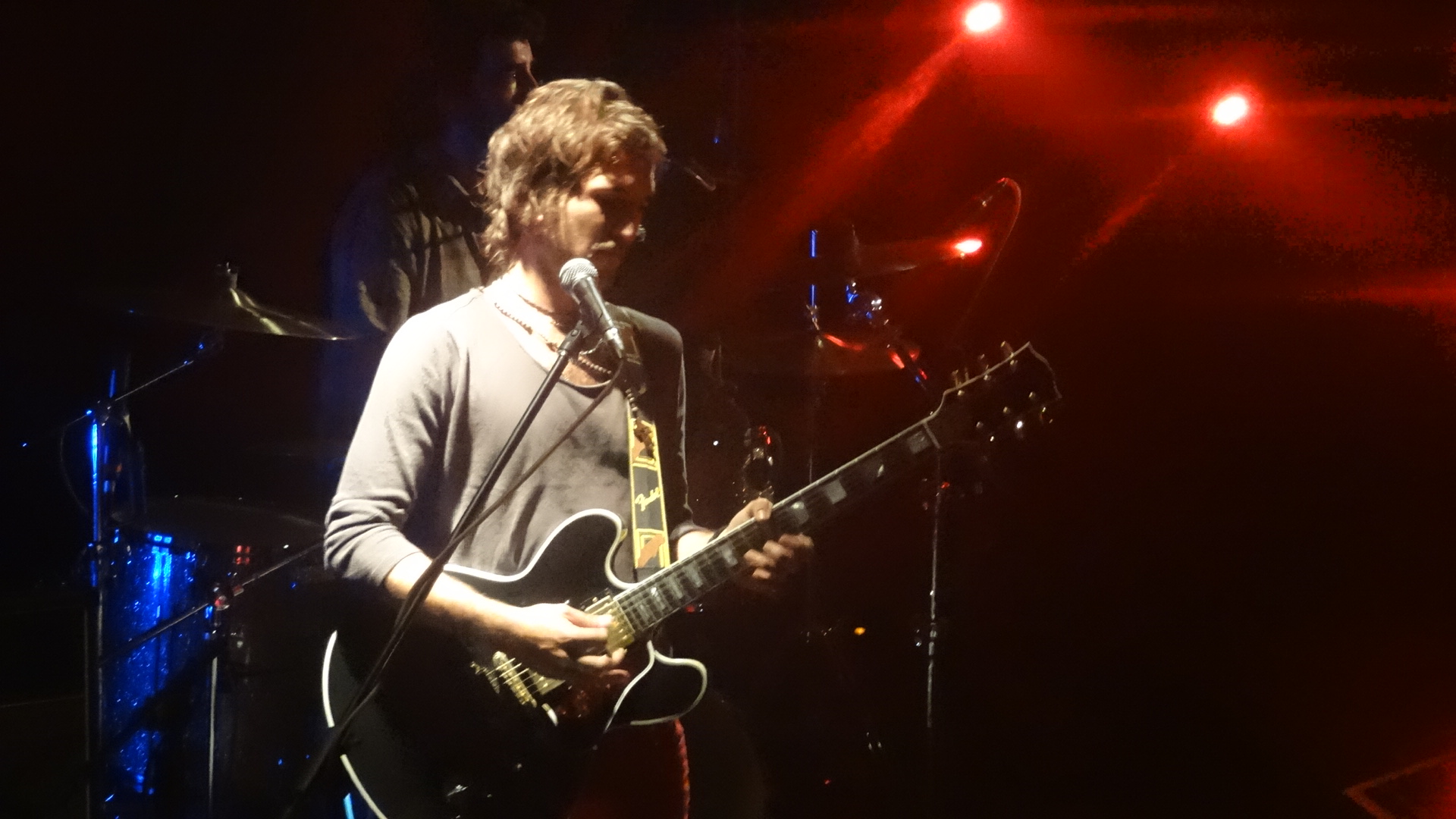 a man singing into a microphone next to a guitar