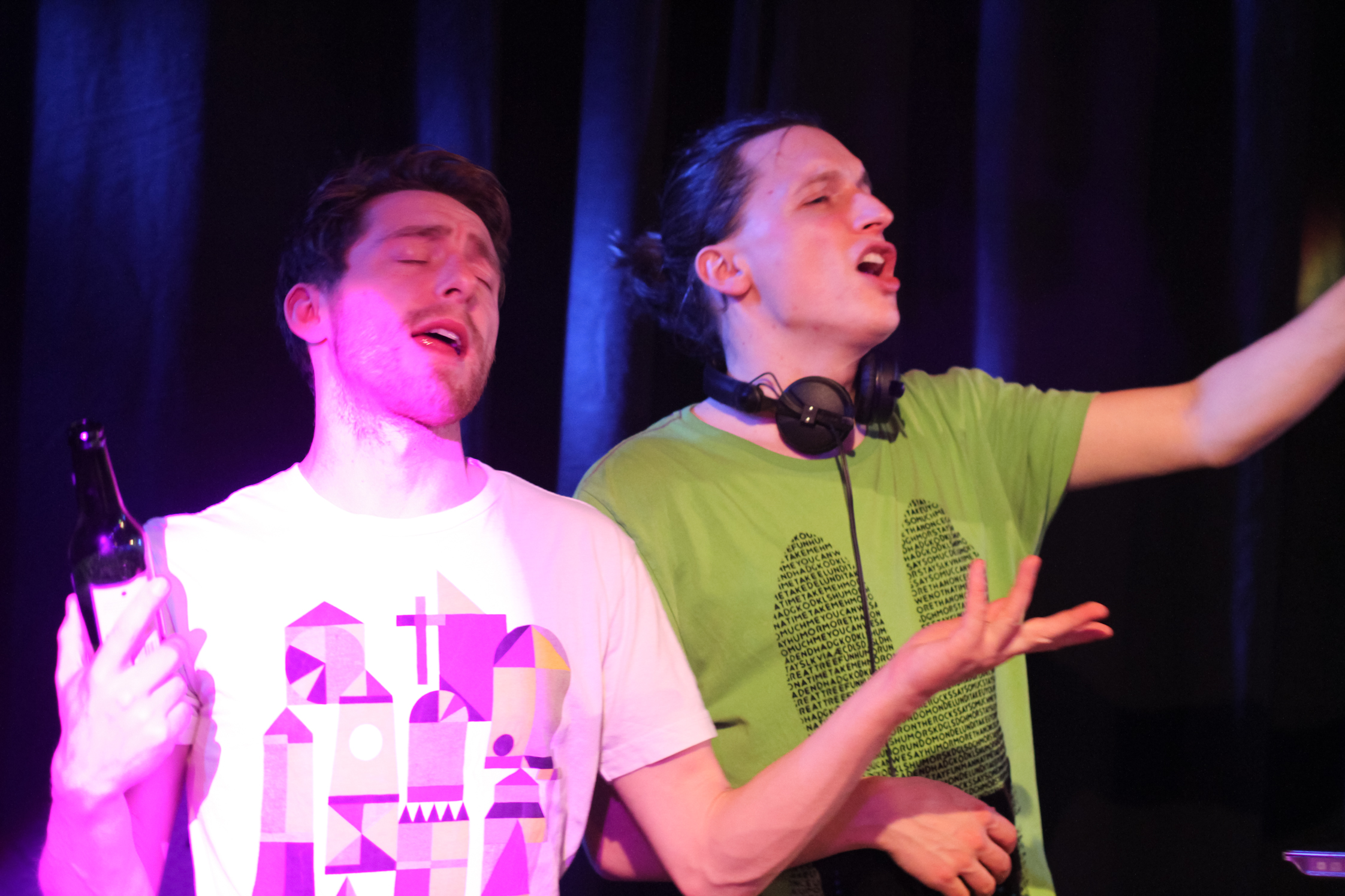 two young men laughing with their arms spread out and they are singing