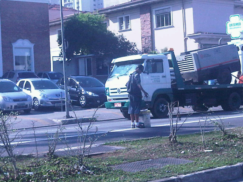 a garbage truck driving down the road in front of some cars