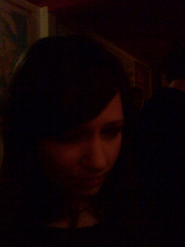 a young woman sits in a dimly lit area